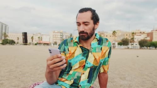 Young man using mobile phone on the beach