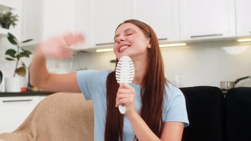 Enthusiastic Young Woman Singing into a Hairbrush at Home