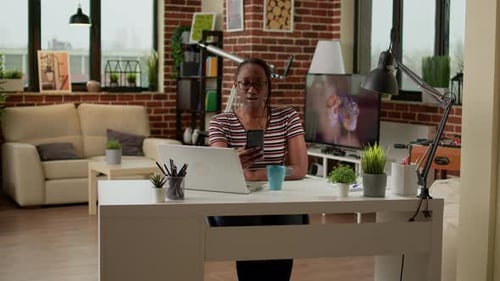 Woman Using Smartphone at Desk in Apartment