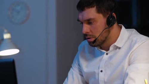 Man in headset working late at computer
