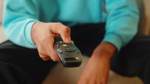African American Man Watching Tv Using Remote Controller
