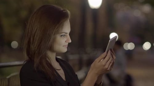 Young Woman Using Tablet Computer In The Park At Night