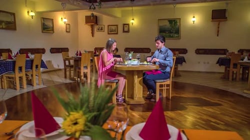 Young beautiful couple dressed formally, having a romantic dinner date at the restaurant. Rotating.