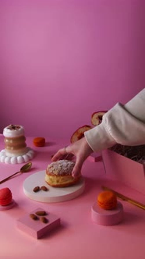 Hand Takes Donut From Display of Pink Sweets