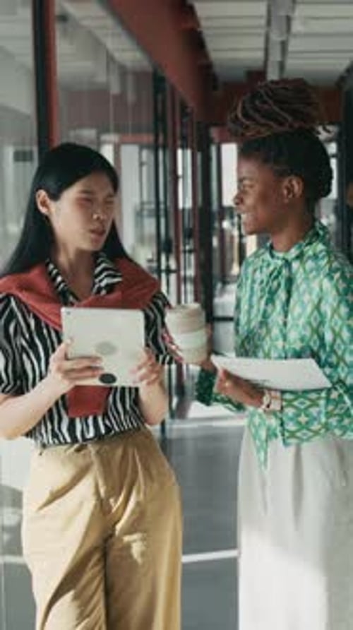 Vertical de femmes d'affaires positives avec des médecins discutant dans le couloir du bureau