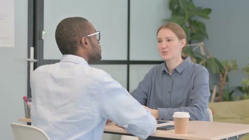 Young Woman Talking to African Man in Office