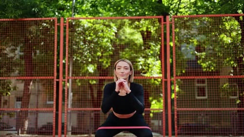 Woman Doing Squats with Resistance Band Outdoors