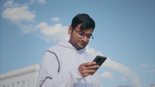 Young Man Using Mobile Phone Outdoors on Sunny Day