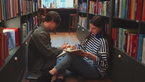 Students Deeply Engrossed in Reading and Discussing Book Together in Library