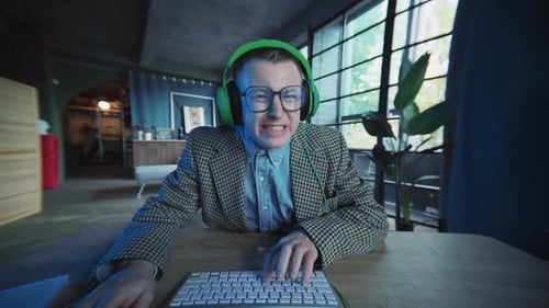 Funny Active Guy with Glasses and Headphones Use Computer Typing on Keyboard Man Looking Geek Office