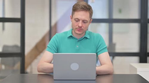 Man Typing on Laptop in Modern Office