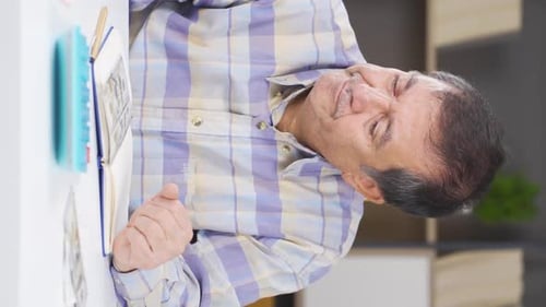 Tired Man Writing at Table Indoors Daytime