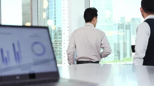 Businessmen Discussing Business by an Office Window