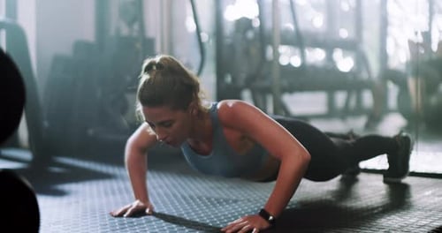An attractive young sportswoman doing push ups while working out in a gym