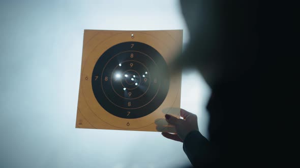 Woman Inspecting Bullet Holes in Paper Shooting Target, Industrial ...