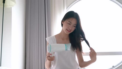 Woman Drying Hair with Hairdryer in Bright Room