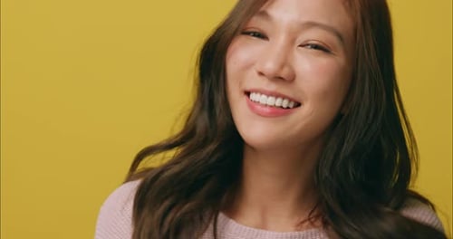 Smiling Woman with Wavy Hair Posing on Yellow