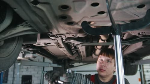 Mechanic Repairing Car Undercarriage in Auto Repair Shop