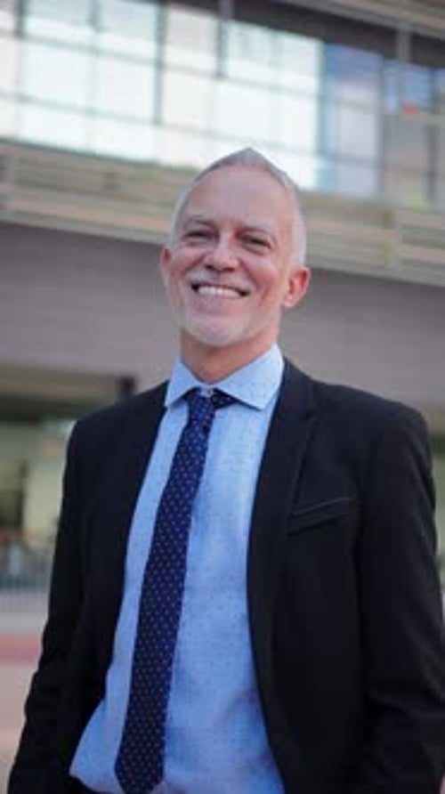 Empresario seguro sonriendo con un traje a medida mientras está de pie al aire libre con un profesional
