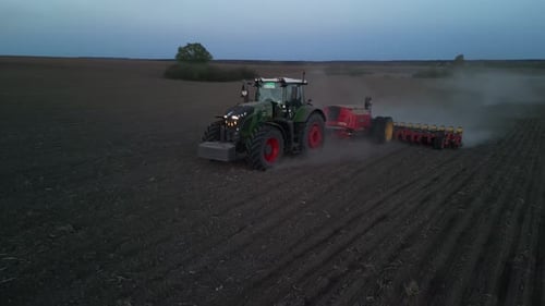 Green tractor works on the field sowing sunflower. Tractor planting corn in Ukraine