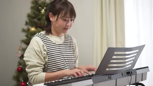 Woman Playing Christmas Music on Keyboard at Home