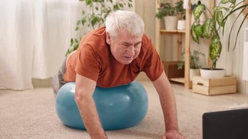 Mature Senior Man Doing Fitness Exercises Gymnastics at Home Online Lesson with Laptop Pc Talking