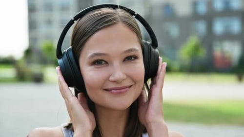 Woman Listening to Music on Headphones in City