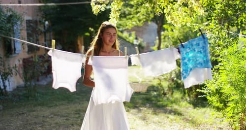 Young Woman Hanging Baby Clothes on Clothesline