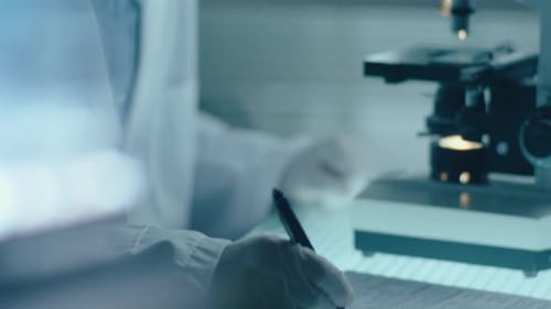 Scientist Viewing Sample Through Microscope in Lab