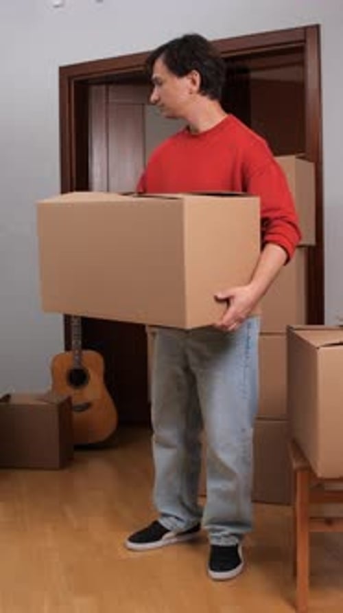 Young Adult Carrying Moving Box Indoors
