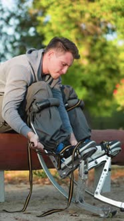 Jeune homme ajustant les sangles sur échasses sur une bûche dans un parc