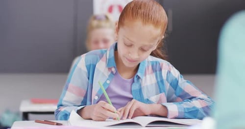 Girl Writes in Classroom, Looks Up Smiling