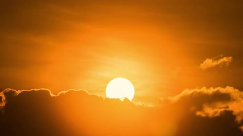 Timelapse of dramatic sunrise with orange sky in a cloudy day.