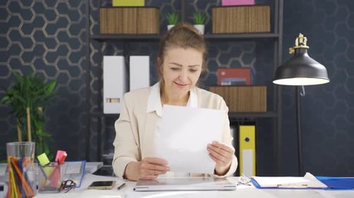 Woman Reviews Document with Positive Reaction at Desk