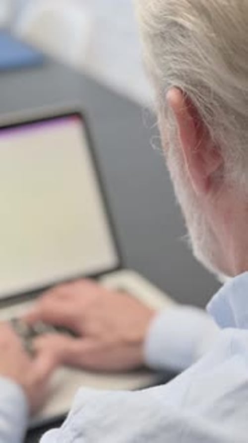 Back View of Old Man Typing on Laptop, vertical video