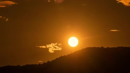 Fiery Sunset Behind Mountain Silhouette with Moving Clouds