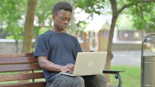 Man Works on Laptop in Park, Neck Pain