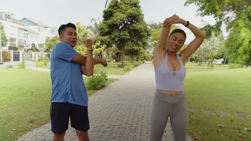 Intercultural Man and Woman Practicing Stretching Exercises in City Park