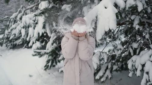 Woman Blowing Snow In Snowy Forest