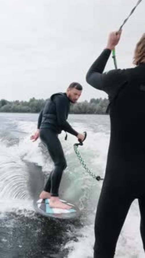 Man Wake Surfing on River With Friend Onlooker