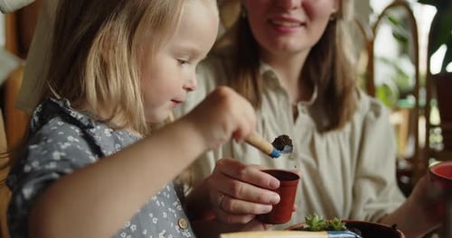 Closeup of Mother and Her Adorable Daughter Replanting an Ornamental Plant