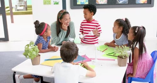 In school, teacher engaging with students around table, discussing project