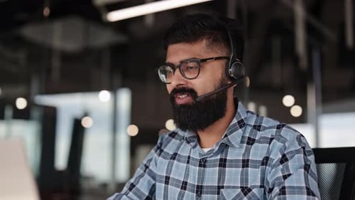 Businessman in Headset Having Video Call on Laptop in Office