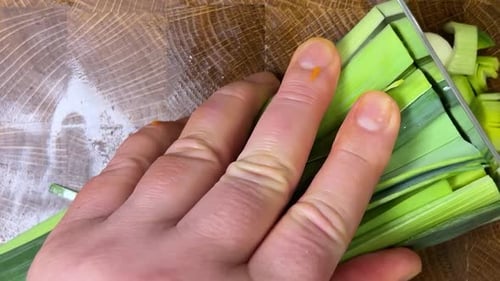 Close-up of Hand Slicing Fresh Green Leeks