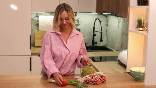 Mujer joven desempaca verduras frescas del mercado local en una cocina moderna y un estilo de vida ecológico