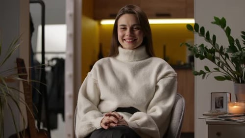 Smiling Woman with Long Hair Sits Indoors