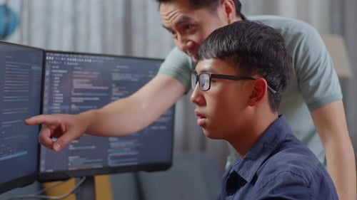 Close Up Of Asian Boy Students Studying Software Code From Male Teacher Or Father