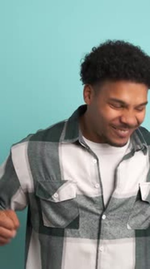 Successful Young Man Clenching Fists in Blue Studio