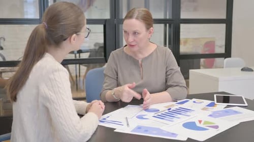 Women Discussing Charts and Shaking Hands in Office