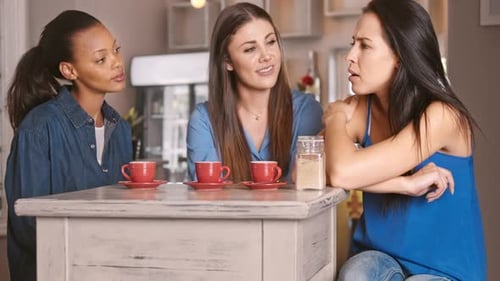 Three women at cafe talking over coffee